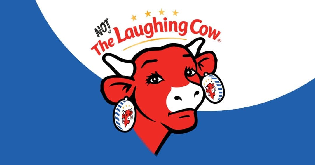 The image features a vibrant red cow with white spots on its face and ears, wearing a pair of earrings with blue and white stripes and a white star. The cow's head is tilted slightly to the left, and it has a white nose and a small, simple smile. Above the cow's head, the text "NOT The Laughing Cow" is written in bold