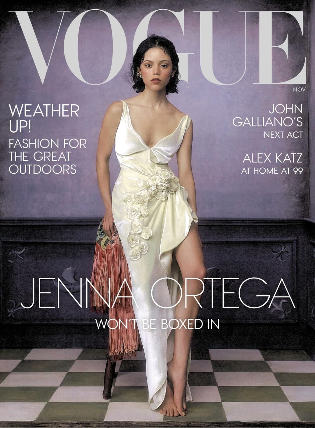 The image is a magazine cover for Vogue, featuring Jenna Ortega. She is elegantly dressed in a white dress adorned with pink flowers, and is barefoot. She is standing on a checkered floor, with a dark-colored, ornate piece of furniture behind her. The cover also includes text that reads "Vogue", "Weather Up!", "Fashion