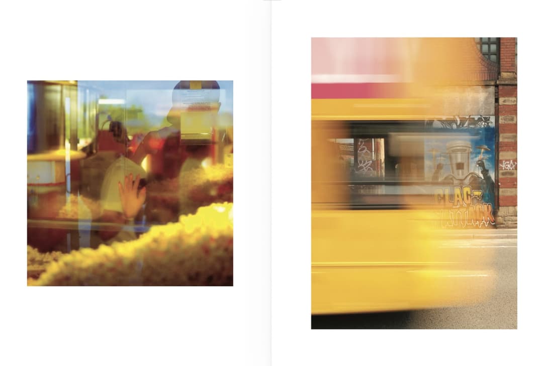 The image is a diptych, a two-part work, divided into two distinct sections. The left section features a close-up of a person's hand reaching towards a glass display case filled with popcorn. The right section shows a blurred image of a yellow bus in motion, with a building featuring a brick facade and a mural in the b