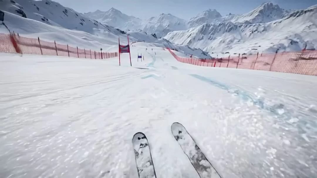 A first-person view shows a pair of skis on a snowy slope lined with orange safety netting, with red and blue gate poles and snowy mountains behind. No legible text is visible.