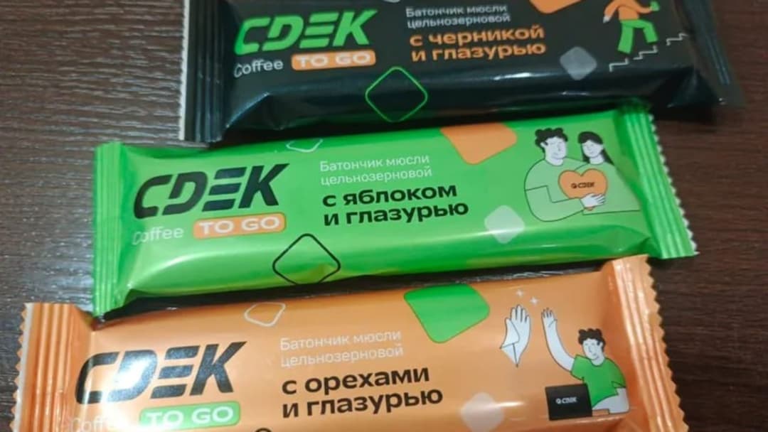 The image shows three packages of CDEK coffee pods, each with a distinct color and design. The top package is black with a green and orange design, featuring the text "Coffee To Go" and a graphic of a person holding a heart. The middle package is green with a black and orange design, featuring the text "Coffee To Go" a