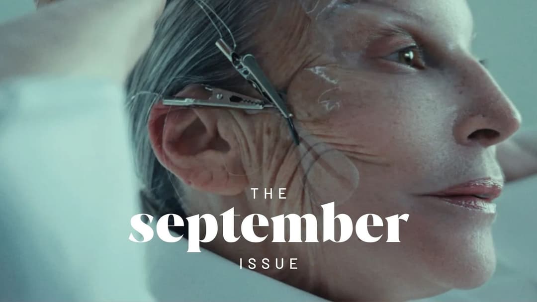 The image shows a close-up of a person's face, likely a woman, with a neutral expression. The person's skin is fair with visible wrinkles and lines, and their hair is gray or silver. A pair of scissors is attached to the person's ear, and a small metal clip is attached to the scissors. The background is a light blue or