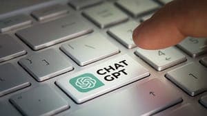 A finger presses a light-green key labeled "CHAT GPT" with the OpenAI logo on a silver keyboard.