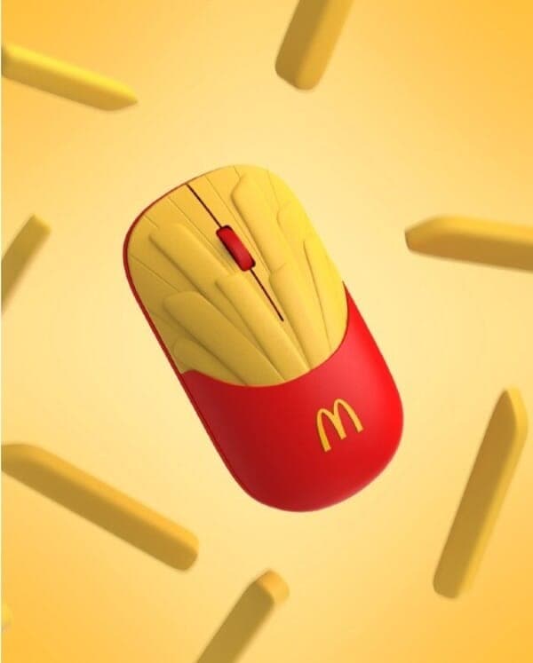 The image presents a computer mouse designed in the shape of a French fry. The mouse is predominantly red with a yellow/gold colored section on the top, resembling the crispy exterior of a fry. The mouse has a red button on the top and a yellow/gold colored section on the bottom, which features the McDonald's logo. The