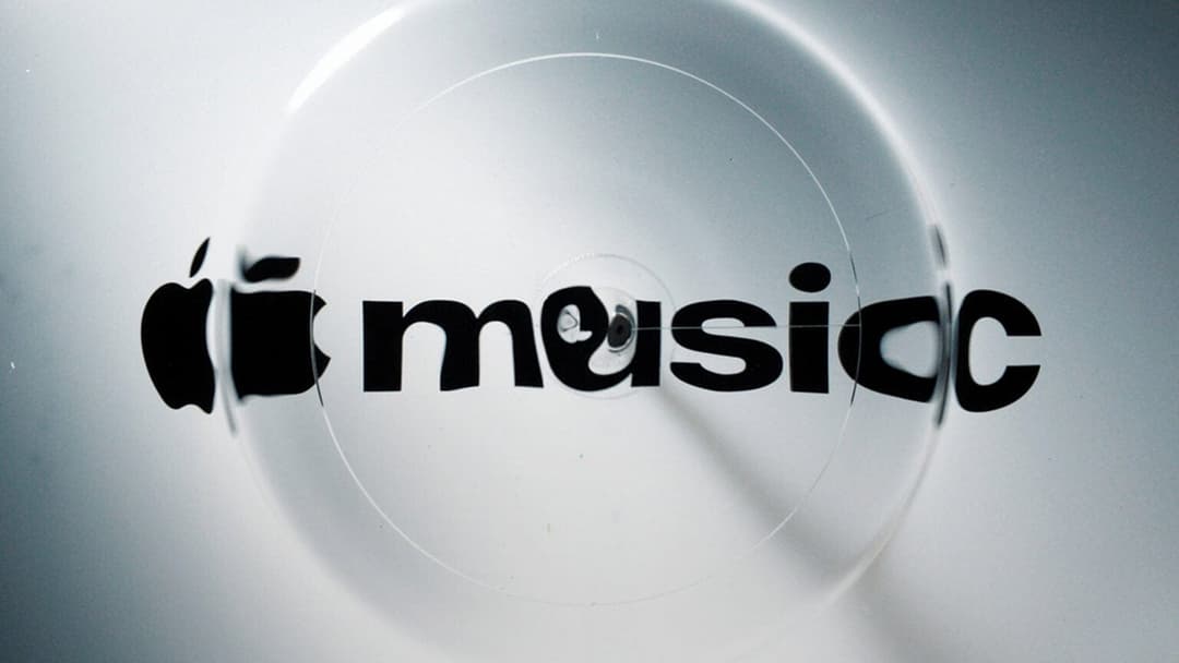 The image shows a close-up view of a white surface with a clear, circular design. The design features a black Apple logo and the word "music" written in a stylized, black font. The Apple logo is positioned on the left side of the circle, while the word "music" is centered on the right side. The design appears to be a w