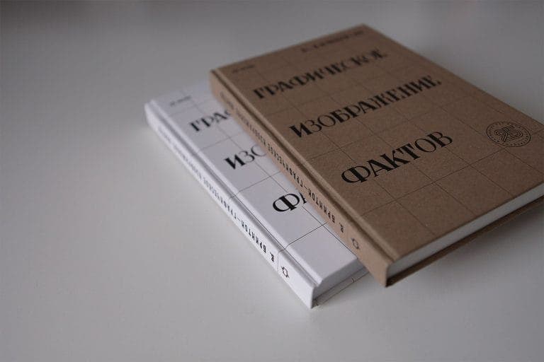 The image shows two books resting on a white surface. The book on the left is white with black text and a grid pattern, and the title "������������������ ��������������" is visible. The book on the right is brown with black text and a grid pattern, and the title "������������" is visible. The books are positioned at an