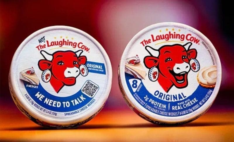 The image shows two round containers of The Laughing Cow brand spreadable cheese wedges. The containers are white with a blue and red label featuring a red cow's head and the text "The Laughing Cow" and "We Need to Talk". The label also indicates that the cheese is made with real cheese and contains 8 original protein-