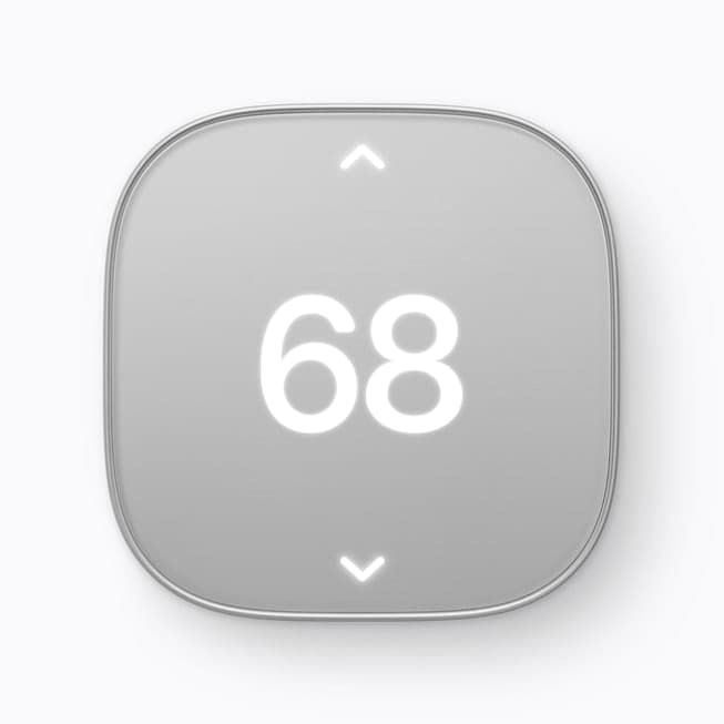 The image shows a gray square-shaped thermostat with a silver border. The thermostat has a slightly rounded edge and features a white number "68" prominently displayed in the center. Above the number, two white arrows point upwards. Below the number, two more white arrows point downwards. The thermostat is set against