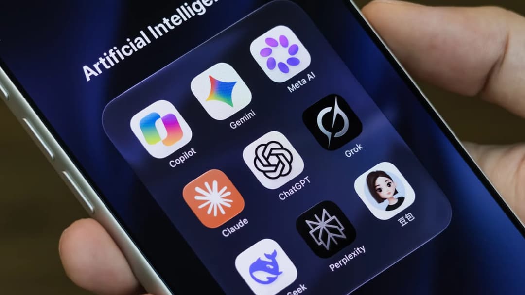 The image shows a person's hand holding a silver iPhone, with the screen displaying a grid of app icons against a dark blue background. The top row features "Artificial Intelligence" and "Meta AI", while the bottom row includes "Copilot", "Gemini", "Grok", "ChatGT", "Claude", "Perplexity", and "Seek". The app icons are