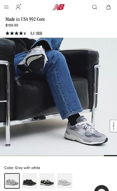 The image shows a person's legs and feet, clad in blue jeans and gray New Balance sneakers, resting on a black leather armchair. The person is wearing black socks. The image is part of a product listing on a website, as indicated by the text "Made in USA 992 Core $199.99". The website also displays a 4.4 rating and a l