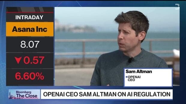 The image shows a Bloomberg TV news broadcast featuring Sam Altman, the CEO of OpenAI. The broadcast is titled "OPENAI CEO SAM ALTMAN ON AI REGULATION" and is presented by Bloomberg TV. The screen displays a stock market update for Asana Inc. with a value of 8.07 and a percentage change of 0.57. The broadcast is set ag