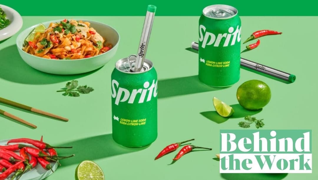 The image presents a vibrant scene set on a green tablecloth. At the center of the image, there are two green Sprite cans, each adorned with a silver straw. The cans are positioned side by side, with the one on the left slightly closer to the viewer. To the left of the cans, there is a white bowl filled with a dish tha
