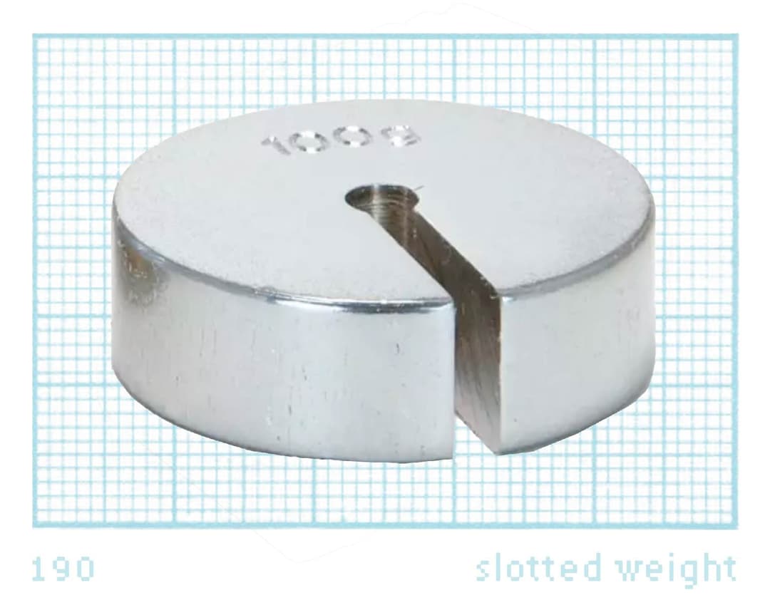 The image shows a silver-colored, circular object with a hole in the center, resting on a blue grid background. The object has the number "100g" inscribed on its surface. The object is labeled "slotted weight" at the bottom right corner.