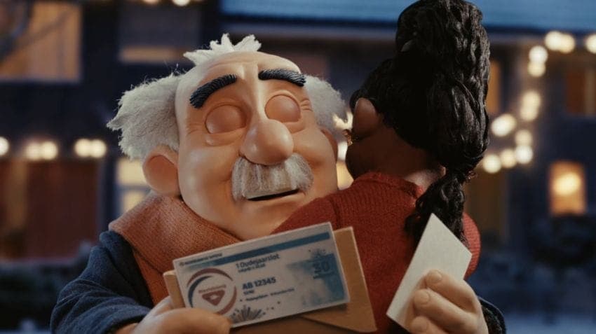 The image shows a puppet character, possibly a man, with white hair and a mustache, holding a blue and white ticket. The ticket appears to be for a bus or train, as indicated by the text "10 Duursgatan" and "AB 12345". The puppet is embracing a smaller puppet, possibly a woman, who has dark hair and is wearing a red sw