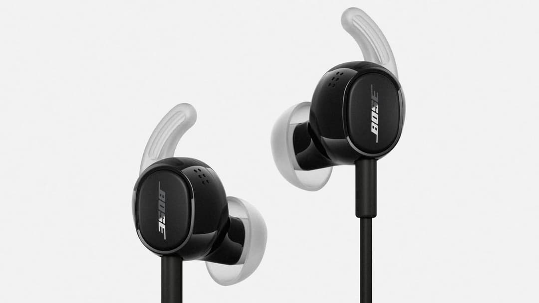 The image shows a pair of Bose earphones, each with a black body and a white earcup. The earcups are attached to the earcups with black earhooks. The Bose logo is prominently displayed on the earcups. The earcups are positioned on either side of the earcups, with the left earcup slightly higher than the right one. The