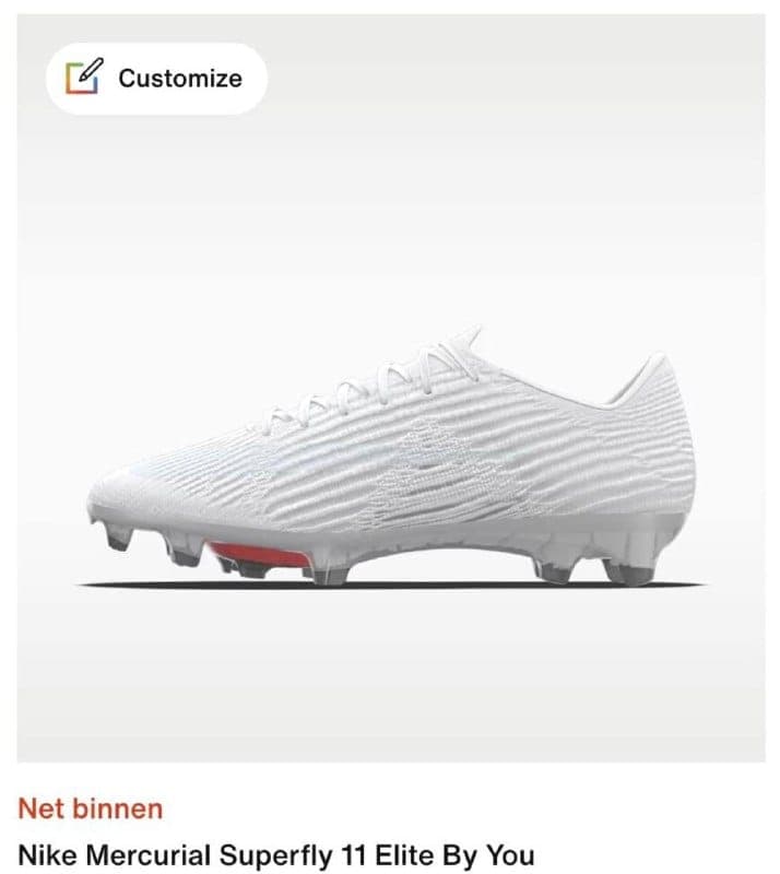 The image presents a white Nike Mercurial Superfly 11 Elite By You soccer cleat, positioned at a slight angle against a white background. The cleat features a distinctive textured pattern on the side, and a red sole is visible at the bottom. The cleat is equipped with black studs. The text "Net binnen" is visible in th
