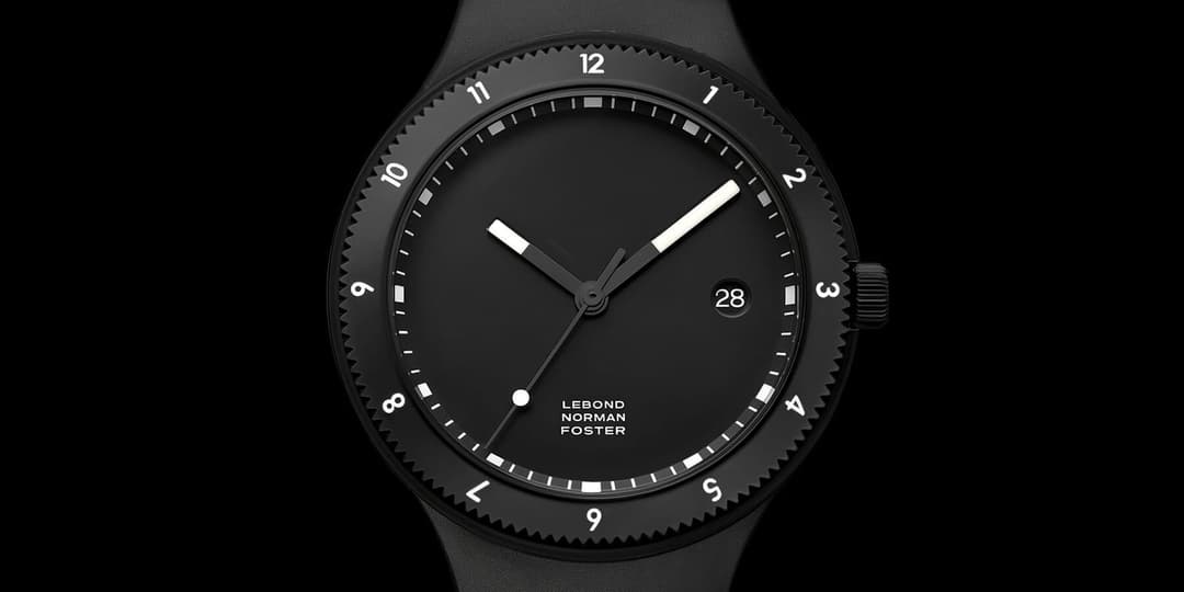 A black Lebond Norman Foster wristwatch with a knurled bezel, luminous hour and minute hands, and a date window showing 28, photographed against a black background. The dial reads "LEBOND NORMAN FOSTER."