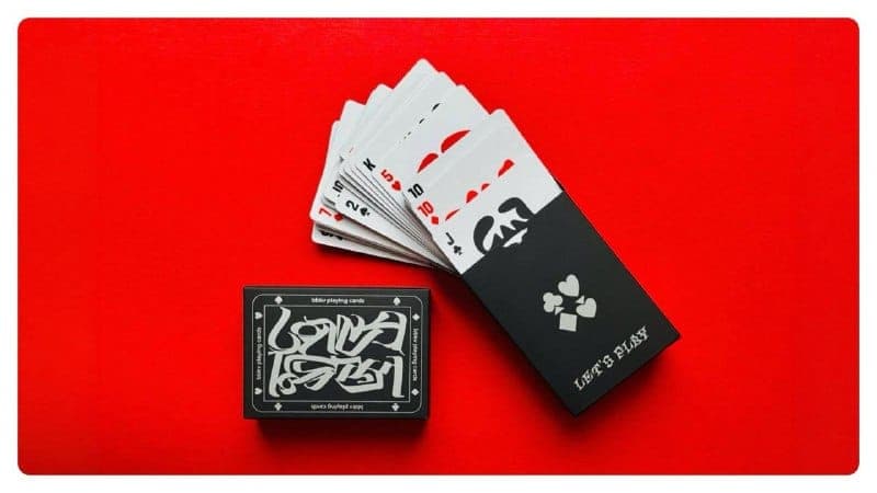 The image shows a collection of playing cards arranged on a vibrant red surface. The cards are predominantly white with black text and symbols, including the numbers 5, 10, and the Ace of Hearts. The cards are neatly arranged in a fan-like pattern, with the Ace of Hearts cards at the top and the other cards in the midd