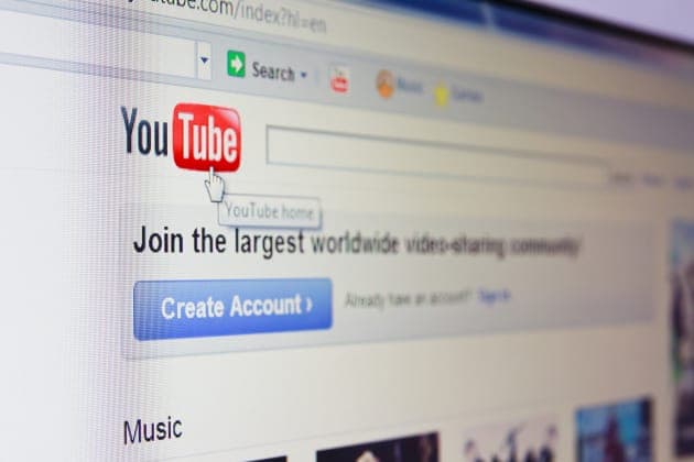 A close-up, angled view of a computer monitor showing the YouTube homepage in a web browser, with the red "You Tube" logo, a "YouTube home" tooltip, the tagline "Join the largest worldwide video-sharing community", a blue "Create Account" button, and a "Music" section heading.