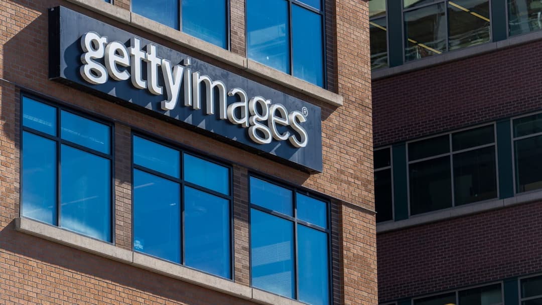 The image shows a modern building with a brick facade and large windows. The building's name, "gettyimages", is prominently displayed in white letters on a black sign attached to the building. The sign is positioned above a row of windows, which are framed in black. The building's brickwork is a reddish-brown color. Th
