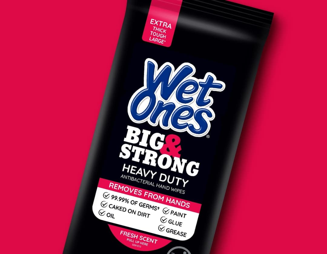 The image shows a black package of Wet Ones Big & Strong Heavy Duty antibacterial hand wipes. The package is standing upright against a vibrant red background. The label on the package is predominantly black with white and red text. The label prominently displays the brand name "Wet Ones" in a blue font, with "Big & St